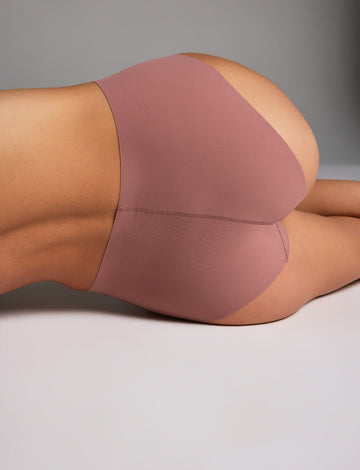 In a studio setting, Holly wears the Whipped Knit No-Show Highwaist Brief in Plum, shown in a close-up back view to highlight the high-waisted cut and smooth fabric. sizing: Holly wears size Small 
