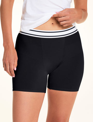 A close-up of Meagan wearing the Cloud Cotton Boxer Brief in Black, paired with a white camisole. The front view highlights the striped waistband, smooth fabric, and fitted mid-thigh silhouette. sizing: Meagan wears size Small