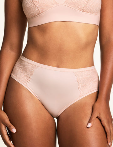 On a light studio backdrop, Amber wears the Bliss Lace Bralette and Bliss Lace Highwaist Brief in Ember Rose, with the lace-trimmed V-neck bralette and high-waisted brief shown from the front. sizing: Amber wears size Medium