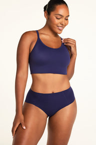 On a warm white studio backdrop, Amber wears the Whipped Knit V-Neck and No-Show Highwaist Brief in Noir, shown from the front with the top’s scoop neckline and wide straps.