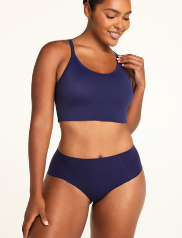 On a warm white studio backdrop, Amber wears the Whipped Knit V-Neck and No-Show Highwaist Brief in Noir, shown from the front with the top’s scoop neckline and wide straps.