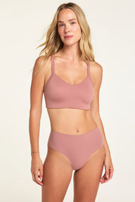On a light studio backdrop, Holly wears the Whipped Knit V-Neck and No-Show Highwaist Thong, both in Plum, shown from the front.