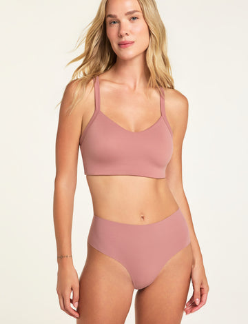 On a light studio backdrop, Holly wears the Whipped Knit V-Neck and No-Show Highwaist Thong, both in Plum, shown from the front.