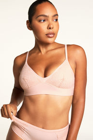 On a warm white studio backdrop, Amber wears the Bliss Lace Bralette in Ember Rose and Bliss Lace Highwaist Brief in Ember Rose, showing the V-neckline, lace detailing across the cups, and high-waisted brief with lace trim. sizing: Amber wears size Medium