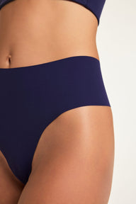 Close-up on a studio backdrop of Holly wearing the No-Show Highwaist Thong in Noir, highlighting the high-waisted front and smooth fabric.