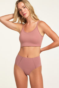 In a studio setting, Holly wears the Whipped Knit No-Show Highwaist Brief in Plum with a matching Whipped Knit Scoop, shown from the front with the high-waisted brief and angled seams visible.