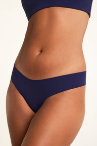 On a white studio backdrop, close-up of the No-Show Low-Rise Thong in Navy, showing the smooth fabric and low-rise waistband.