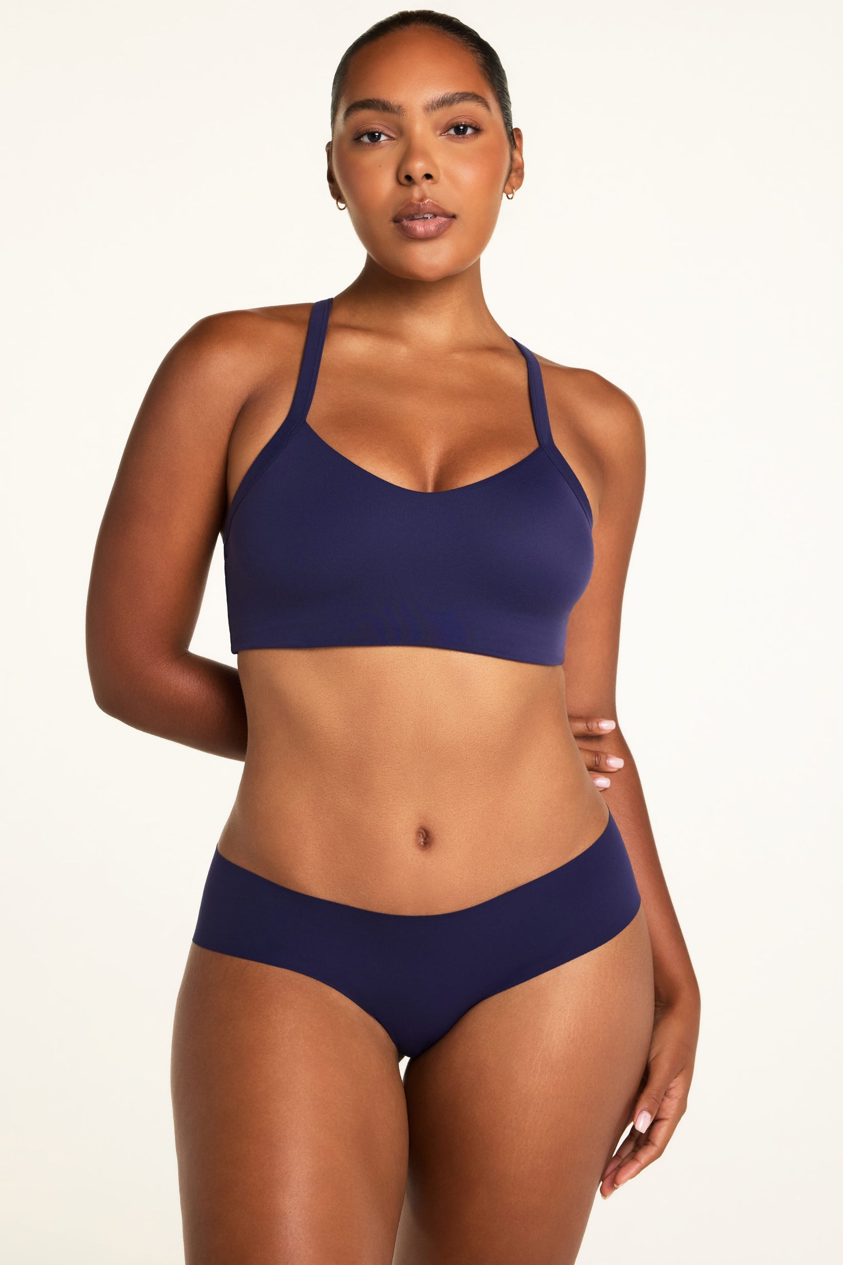 On a light studio backdrop, Amber wears the WhippedKnit V-Neck and No-Show Hiphugger, both in Noir, showing the V-neck top and smooth hiphugger with moderate back coverage.