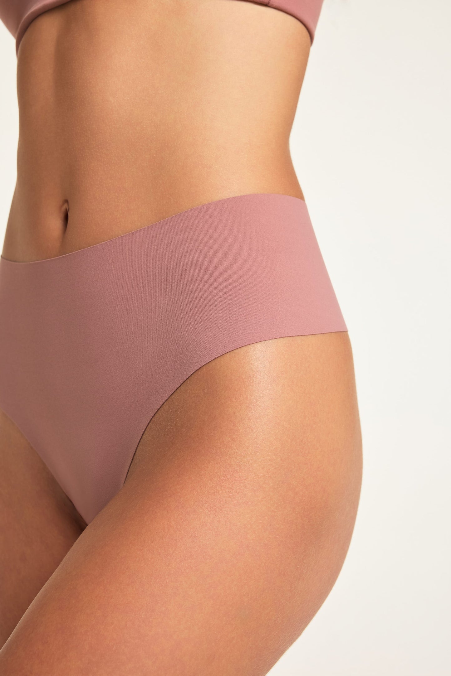 Close-up of Holly wearing the No-Show Highwaist Thong in Plum, showing the high waist and smooth, raw-edge finish.