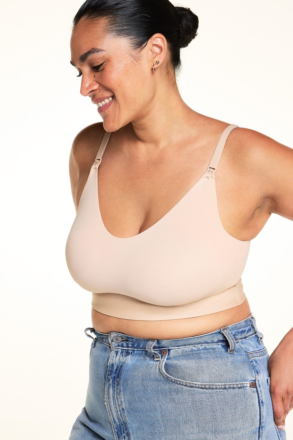 Cropped front view of Jennifer wearing the Bliss Nursing Bralette in Beige with light-wash jeans, highlighting the scoop neckline, nursing clips, adjustable shoulder straps, and wide underband.