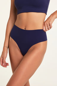 Close-up on a studio backdrop of Holly wearing the No-Show Highwaist Thong in Noir, highlighting the high waist and raw-edge design.
