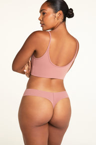 On a white studio backdrop, Amber wears the Whipped Knit Scoop and No-Show Low-Rise Thong in Plum from the back, showing the scoop back and low-rise thong waistband.