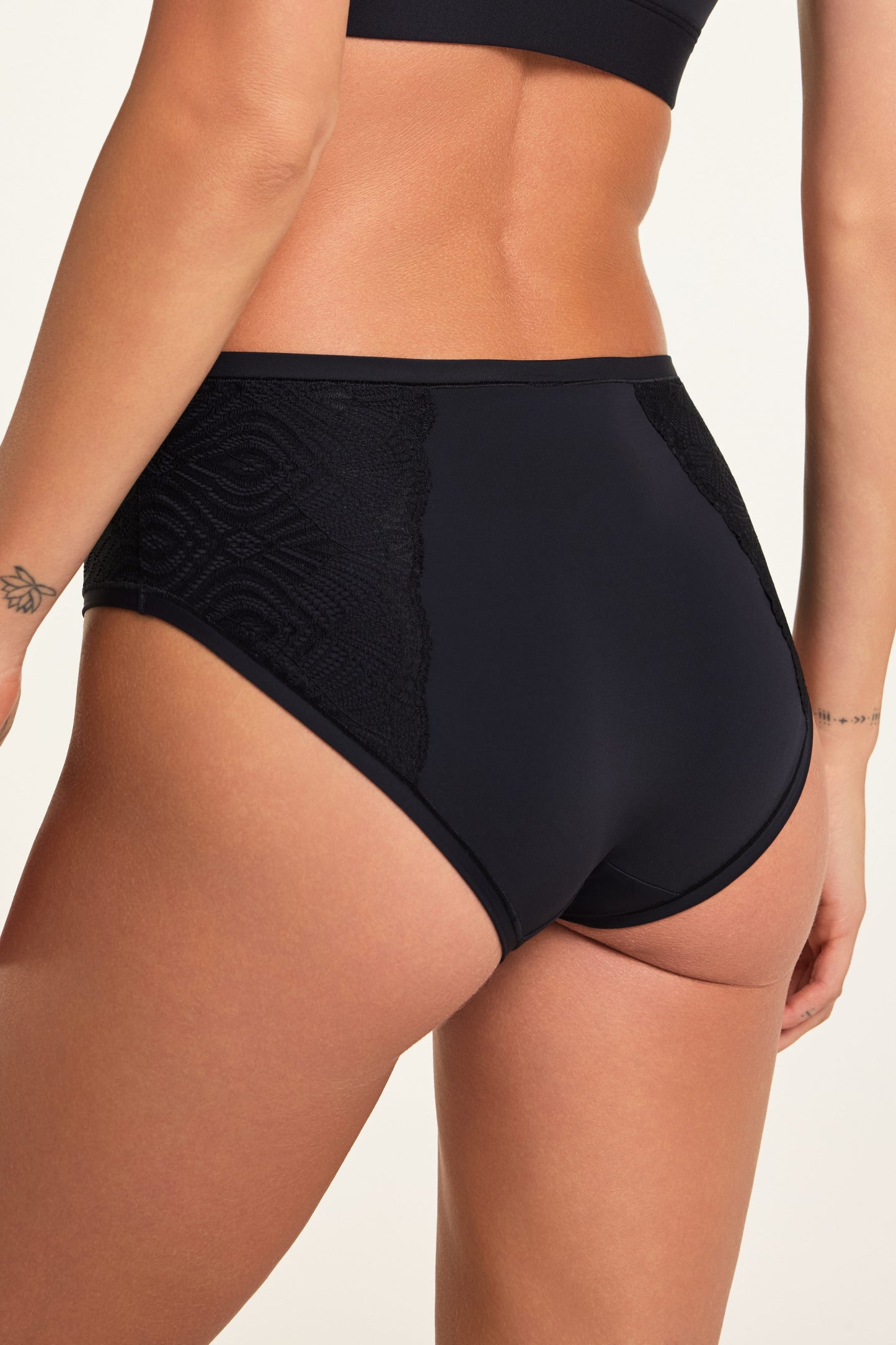 Close-up from the back of the Bliss Lace Highwaist Brief in Black on Holly, showing the high-waisted design and lace panels.