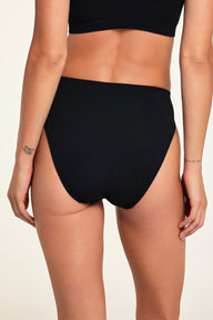Three-quarter back view of the Knit Seamless French Cut Brief in Black paired with the Knit Seamless Bralette in Black.