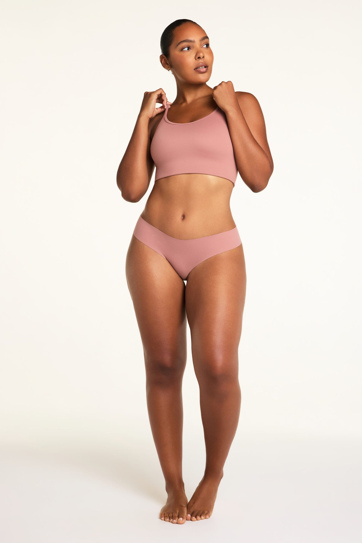 On a white studio backdrop, Amber wears the Whipped Knit Scoop and No-Show Low-Rise Thong in Plum, showing the scoop neckline, slim straps, and coordinating low-rise thong.
