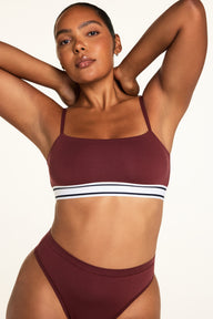 Three-quarter back view of the Cloud Cotton Bandeau Bralette in Cabernet, a wireless bandeau bralette in cloud-soft cotton-modal fabric with thin adjustable straps, no wire or padding, and a stripe-accent elastic underband, paired with the Cloud Cotton Highwaist Thong in Cabernet.