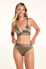 On a light studio backdrop, Meagan smiles while wearing the Stretch Satin Triangle Bralette and Stretch Satin Highwaist Thong in Sable, showing the deep V-neck, adjustable straps, and wide waistband.