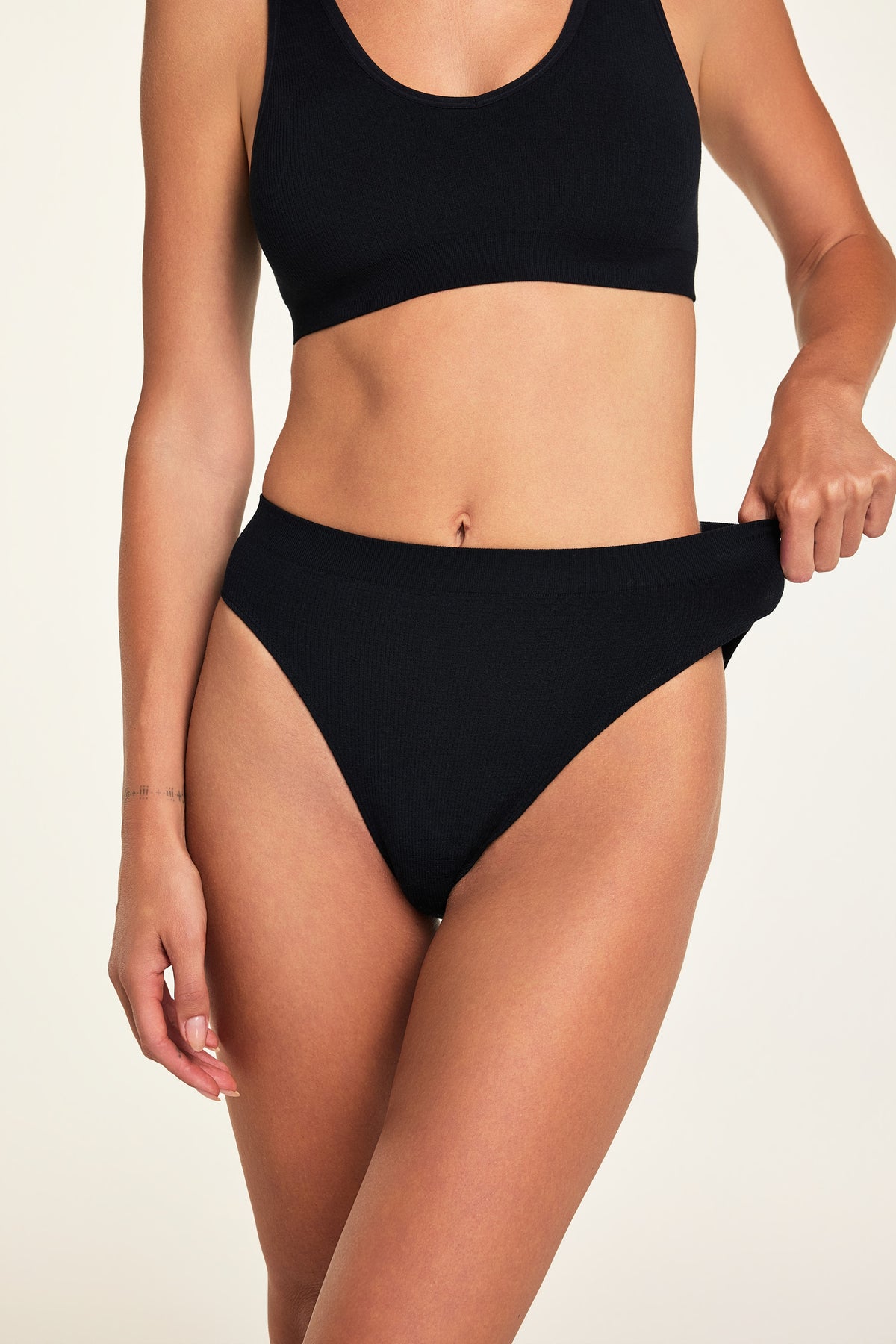 Close-up detail of the Knit Seamless French Cut Brief in Black paired with the Knit Seamless Bralette in Black.