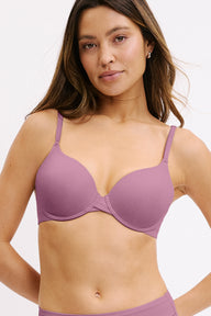 In a white studio setting, Darion wears the Base Bra in Mirage, featuring smooth molded cups, a scoop neckline, and adjustable straps for a customizable fit. sizing: Darion wears size 32D