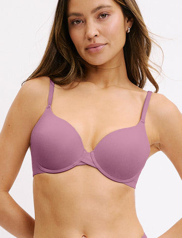 In a white studio setting, Darion wears the Base Bra in Mirage, featuring smooth molded cups, a scoop neckline, and adjustable straps for a customizable fit. sizing: Darion wears size 32D