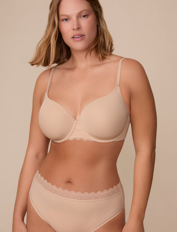 On a neutral studio backdrop, Sonnie wears the Base Lace T-Shirt Bra in Beige with matching underwear. The front view highlights the smooth molded cups, underwire support, adjustable straps, and lace detail at the center gore and waistband. sizing: Sonnie wears size 36E