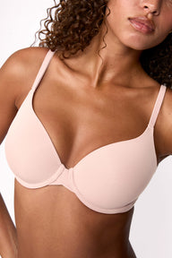 On a light studio backdrop, Courtney wears the Base T-Shirt Bra in Rose, shown in a close-up. The bra features smooth molded cups, a lightly lined design, adjustable straps, and an underwire for support. sizing: Courtney wears size 32D