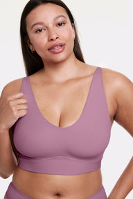 In a studio setting, Alana wears the Bliss Bralette in Mirage, shown in a close-up front view with a scoop neckline, wireless cups, and a smooth, wide underband. The soft fabric provides lightweight, comfortable support. sizing: Alana wears size Large