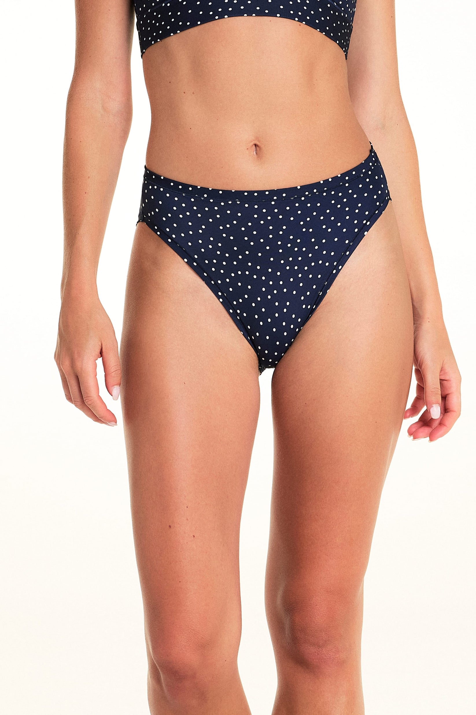 On a light studio backdrop, Alexis wears the Bliss French Cut in Navy Dot. The close-up image highlights the high-cut leg openings, mid-rise waist, and allover white dot print. sizing: Alexis wears size Small