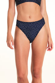On a light studio backdrop, Alexis wears the Bliss French Cut in Navy Dot. The close-up image highlights the high-cut leg openings, mid-rise waist, and allover white dot print. sizing: Alexis wears size Small