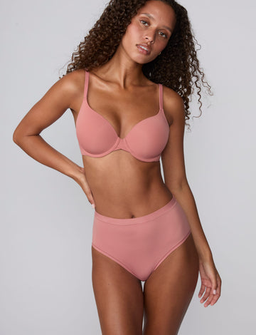 On a light gray studio backdrop, Courtney wears the Bliss Highwaist Brief in Cinnamon with a matching bra. A full-body front view highlights the smooth fabric, high-rise waist, and full-coverage silhouette. sizing: Courtney wears size Small