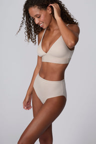 On a light gray studio backdrop, Courtney wears the Bliss Highwaist Brief in Pebble with a matching bra. A three-quarter view highlights the smooth fabric, high-rise waistband, and full-coverage silhouette. sizing: Courtney wears size Small