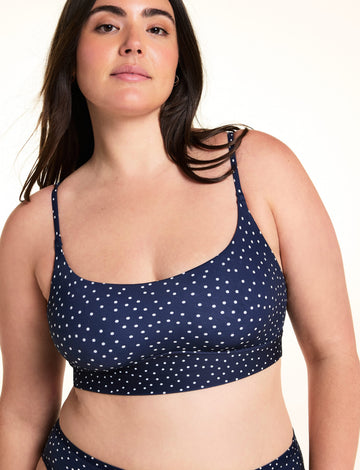 On a light studio backdrop, Alessandra wears the Bliss Scoop Bralette in Navy Dot with matching Navy Dot underwear. The close-up image highlights the scoop neckline, adjustable straps, wide underband, and allover white dot print. sizing: Alessandra wears size Large