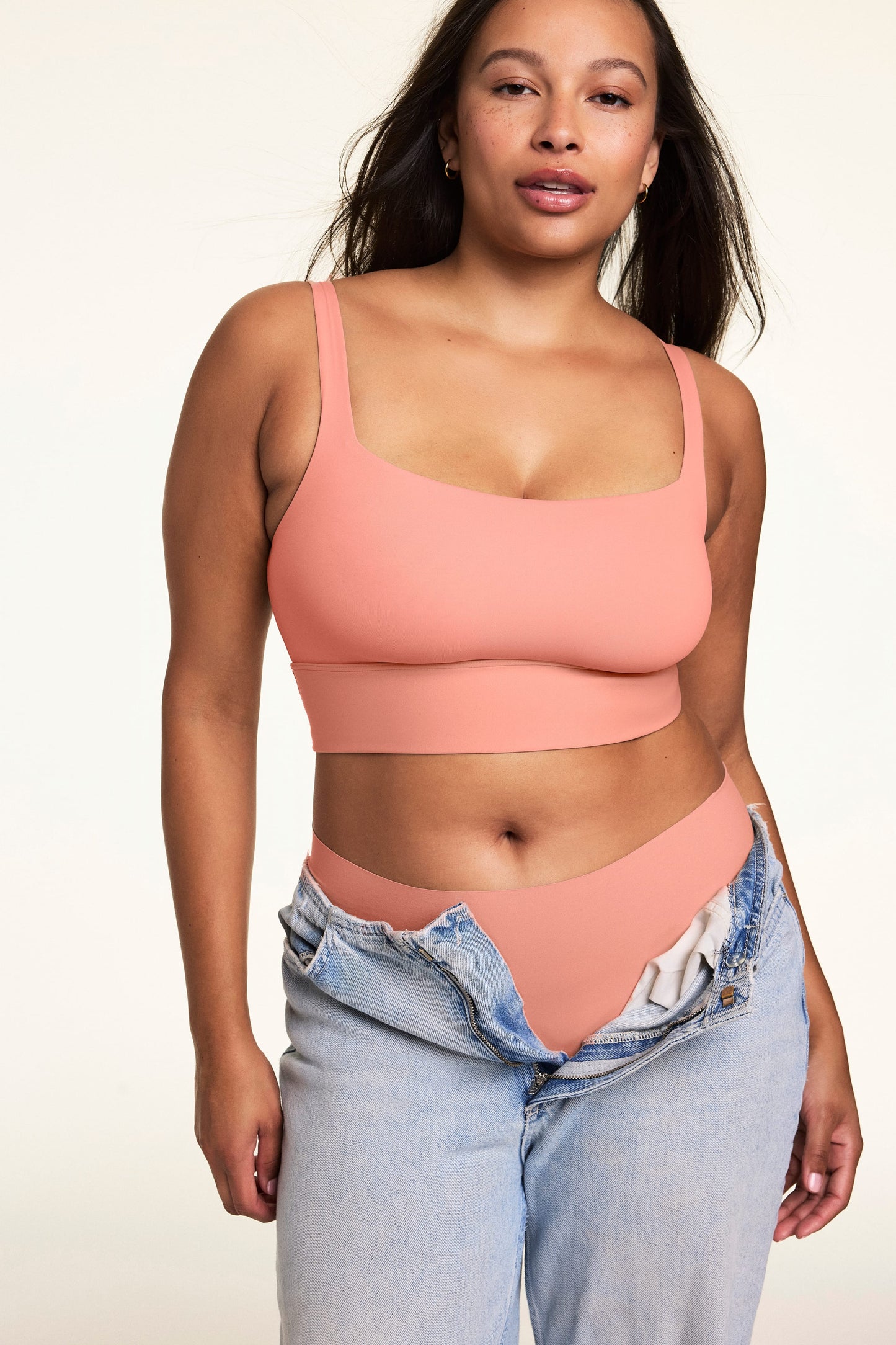 Against a neutral studio backdrop, Alana wears the Bliss Squareneck Bralette in Cabana with matching underwear and low-rise jeans, showcasing the square neckline, wide comfort band, and smooth fit.  sizing: Alana wears size Large