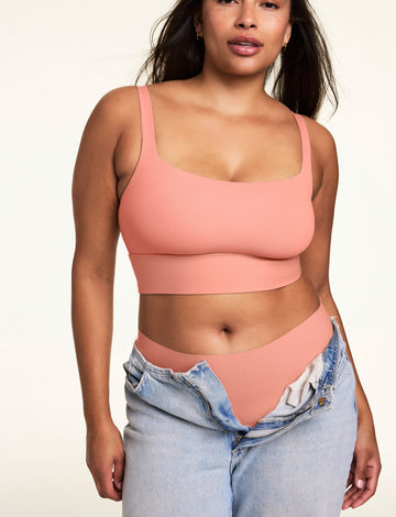 Against a neutral studio backdrop, Alana wears the Bliss Squareneck Bralette in Cabana with matching underwear and low-rise jeans, showcasing the square neckline, wide comfort band, and smooth fit.  sizing: Alana wears size Large