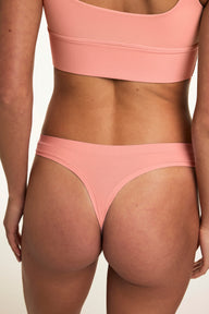 From the back, Gianna wears the Bliss Thong in Cabana with the matching Bliss bralette, showcasing the minimal coverage silhouette, smooth fabric, and soft waistband. sizing: Gianna wears size Small