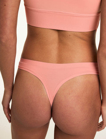 From the back, Gianna wears the Bliss Thong in Cabana with the matching Bliss bralette, showcasing the minimal coverage silhouette, smooth fabric, and soft waistband. sizing: Gianna wears size Small
