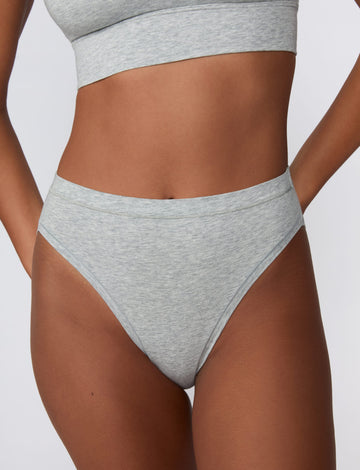 On a light gray studio backdrop, Courtney wears the Cloud Cotton French Cut Brief in Heather Grey. The close-up front view highlights the French-cut leg opening, mid-rise waistband, and soft cotton fabric. sizing: Courtney wears size Small