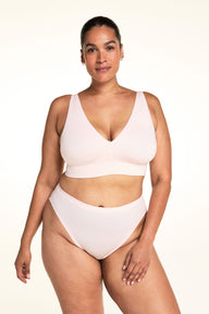 On a light studio backdrop, Jennifer wears the Cloud Cotton French Cut in Dogwood with the Bliss Triangle Bralette in Dogwood. The image highlights the high-cut leg opening, smooth waistband, and soft cotton fabric. sizing: Jennifer wears size Large
