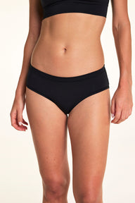 Against a neutral studio backdrop, Alexis wears the Cloud Cotton Hiphugger underwear in Black, featuring a low-rise silhouette, soft waistband, and everyday coverage. sizing: Alexis wears size Small