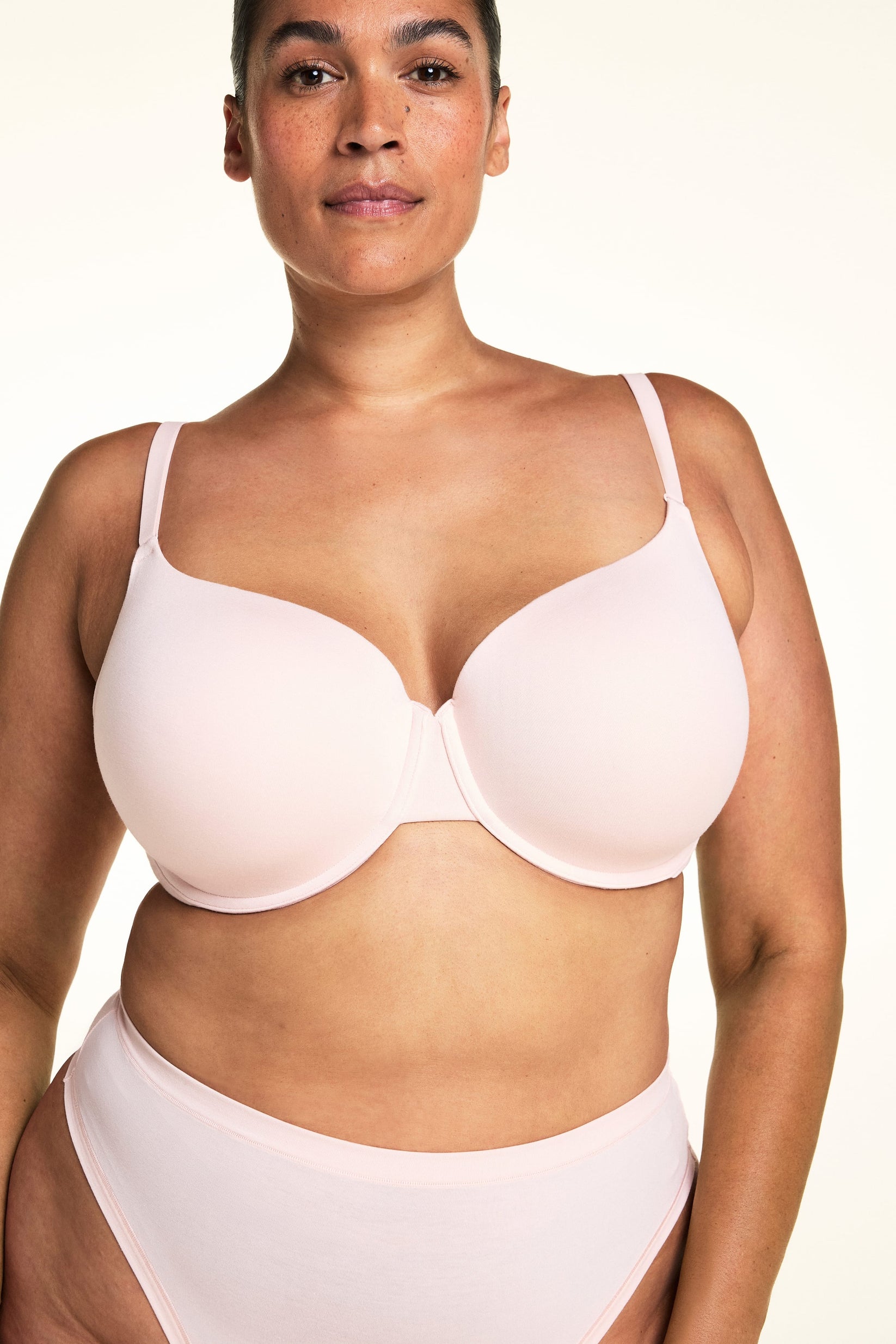 On a light studio backdrop, Jennifer wears the Cloud Cotton T-Shirt Bra in Dogwood paired with matching underwear. The close-up view highlights the smooth molded cups, underwire support, and adjustable straps.  sizing: Jennifer wears size 38DDD