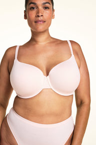 On a light studio backdrop, Jennifer wears the Cloud Cotton T-Shirt Bra in Dogwood paired with matching underwear. The close-up view highlights the smooth molded cups, underwire support, and adjustable straps.  sizing: Jennifer wears size 38DDD