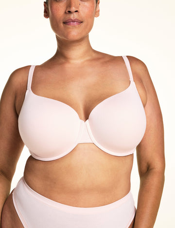 On a light studio backdrop, Jennifer wears the Cloud Cotton T-Shirt Bra in Dogwood paired with matching underwear. The close-up view highlights the smooth molded cups, underwire support, and adjustable straps.  sizing: Jennifer wears size 38DDD