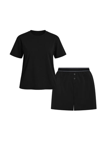 Flat lay of the Cloud Cotton Sleep Set in Black, featuring a short-sleeve tee with chest pocket and matching boxer-style sleep shorts. The shorts have a button fly and tonal waistband with a thin black stripe detail. Displayed against a white background for a clean, minimal presentation.