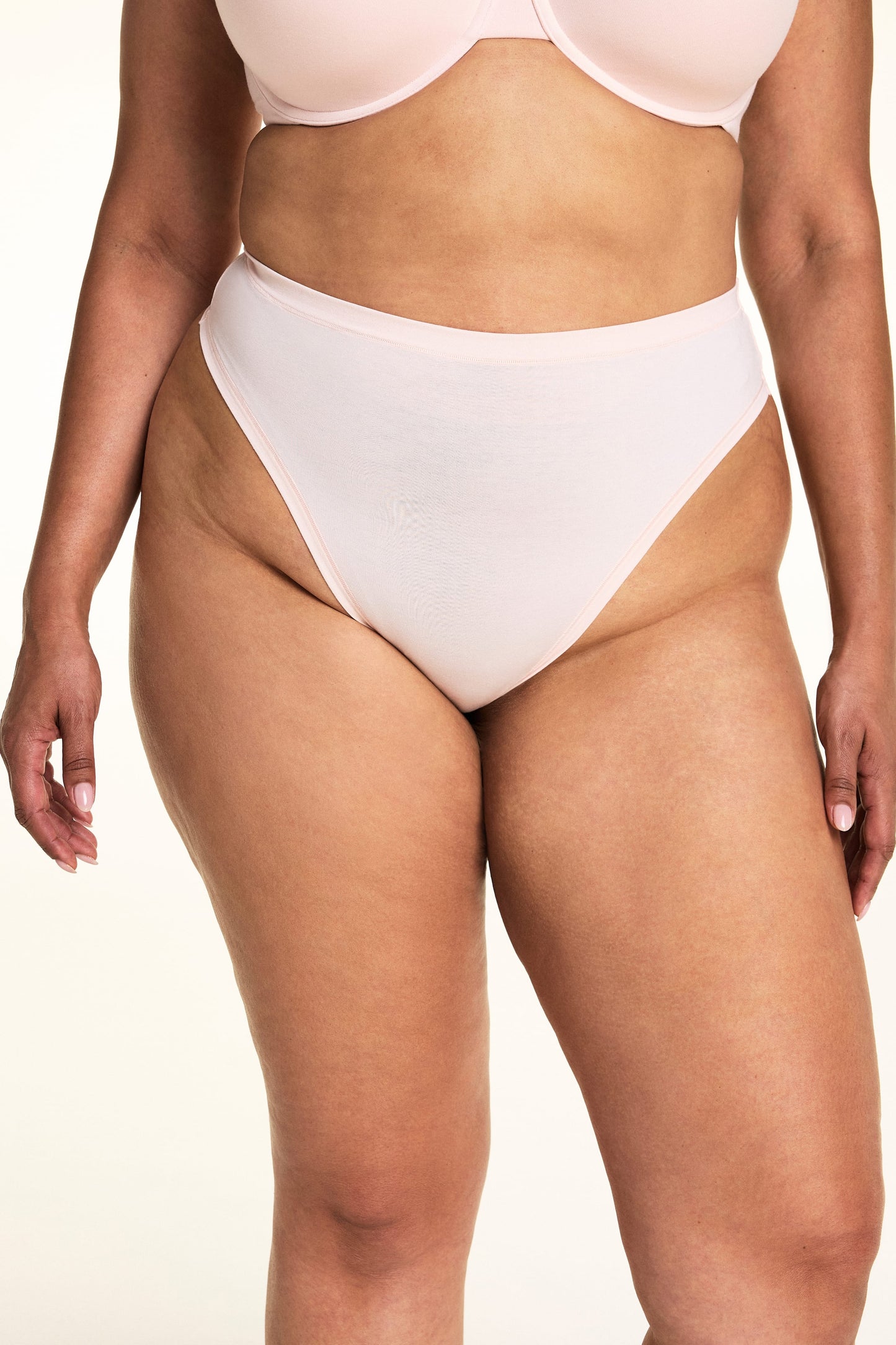 On a light studio backdrop, Jennifer wears the Cloud Cotton Highwaist Thong in Dogwood. The close-up highlights the high-rise waistband, high-cut leg opening, and soft cotton fabric. sizing: Jennifer wears size XL