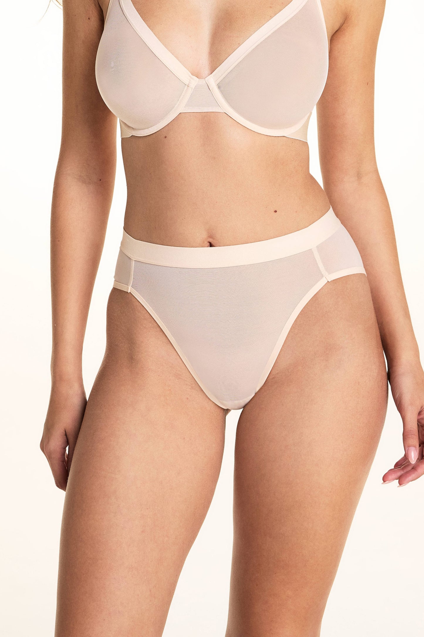 On a light studio backdrop, Laura wears the ComfortMesh™ Plunge Bra and ComfortMesh™ Highwaist Brief in Pearl. The high-rise brief features soft sheer mesh fabric, a wide waistband, and moderate back coverage. 