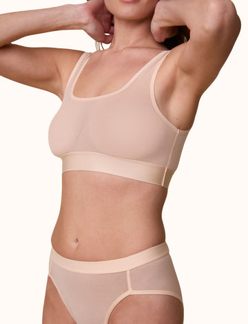 3/4th profile of the model wearing the ComfortMesh™ Scoop Bralette in Pearl. The wide, supportive band and soft, flexible fabric create a comfortable fit. sizing: Gracie wears a size Small