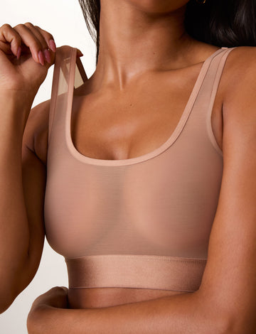 On a light studio backdrop, Ally wears the ComfortMesh™ Scoop Bralette in Taupe. A close-up view highlights the scoop neckline, sheer mesh fabric, wide comfort band, and double shoulder straps. sizing: Ally wears size Small