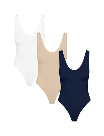 Product shot of Harper Wilde The Bodysuit Trio — three Bliss scoop-neck bodysuits in White, Beige, and Navy, smooth and close-to-body for layering under fall bottoms