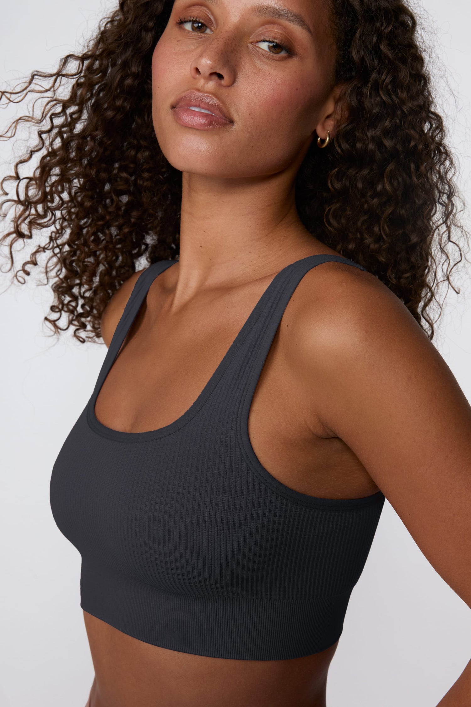 In a studio setting, Courtney wears the Ribbed Seamless Scoop Bralette in Charcoal. A close-up view highlights the scoop neckline, wide straps, ribbed texture, and supportive underband. sizing: Courtney wears size Small