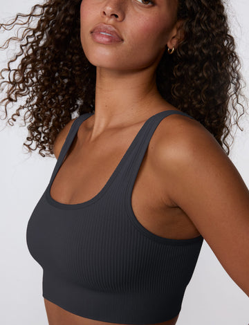 In a studio setting, Courtney wears the Ribbed Seamless Scoop Bralette in Charcoal. A close-up view highlights the scoop neckline, wide straps, ribbed texture, and supportive underband. sizing: Courtney wears size Small